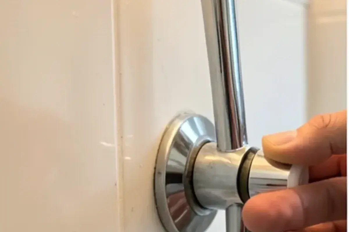 Hand turning the rotational limit stop on a single-handle shower valve to correct lukewarm showers
