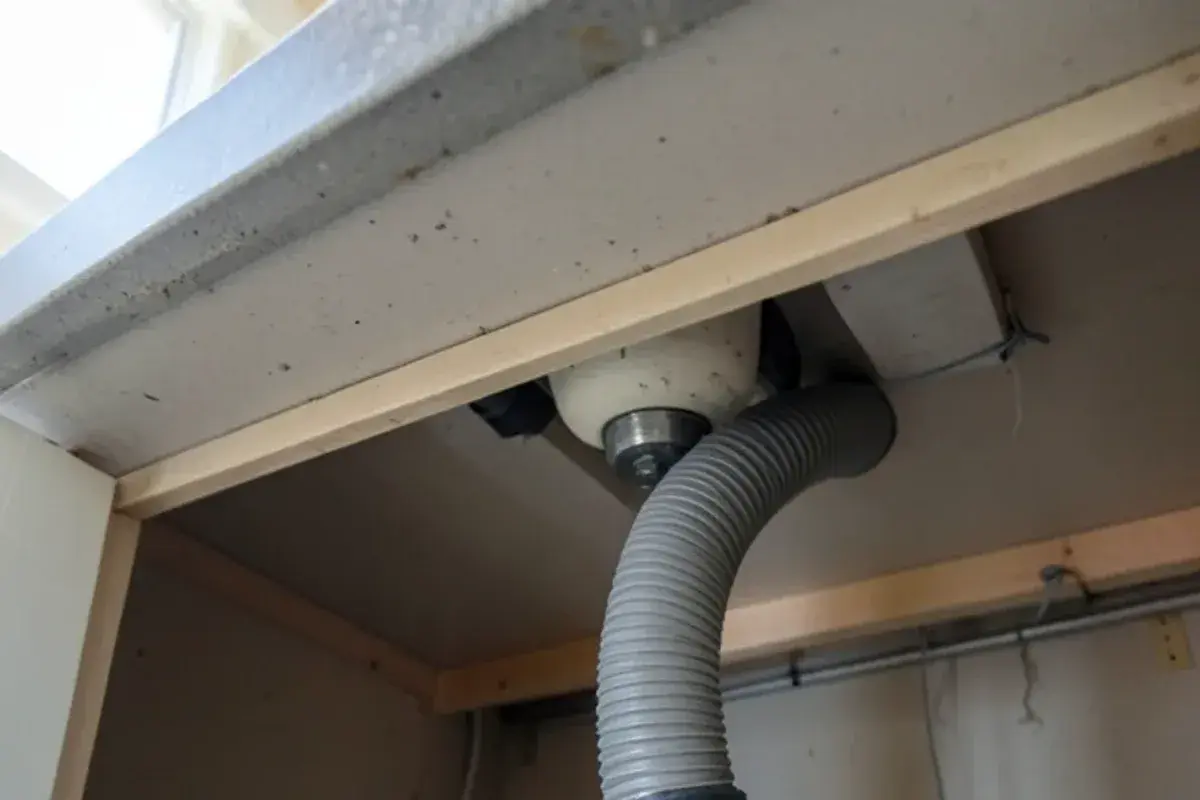 Dishwasher drain hose looped and strapped to the underside of the countertop for a dishwasher drain hookup